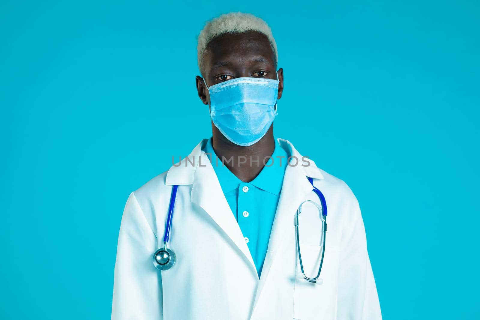 Portrait of african doctor in professional medical coat and mask. Doc man isolated on blue background
