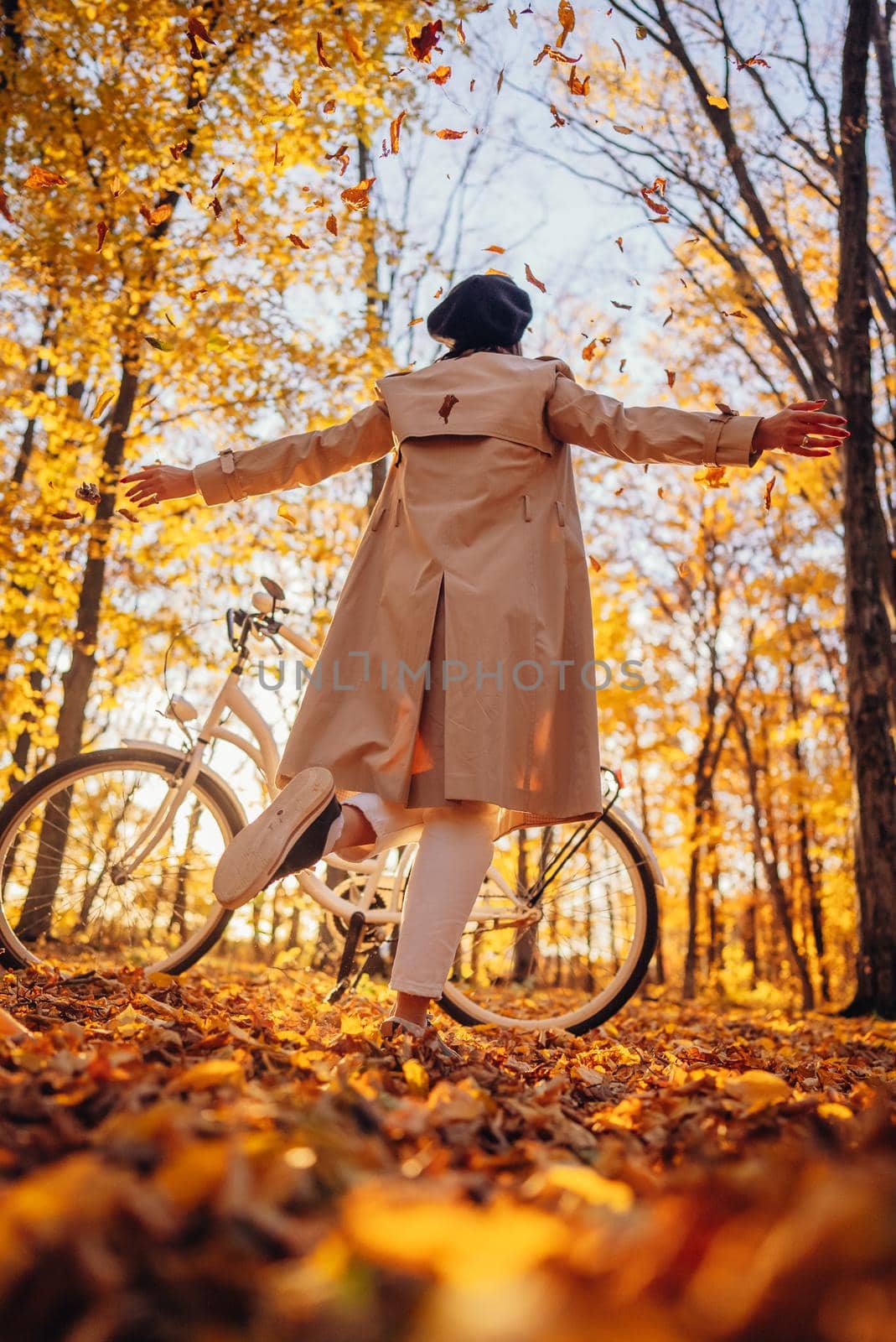 Young pretty woman enjoying autumn nature near vintage white bicycle. Lady having fun on orange nature fall background in park. High quality photo