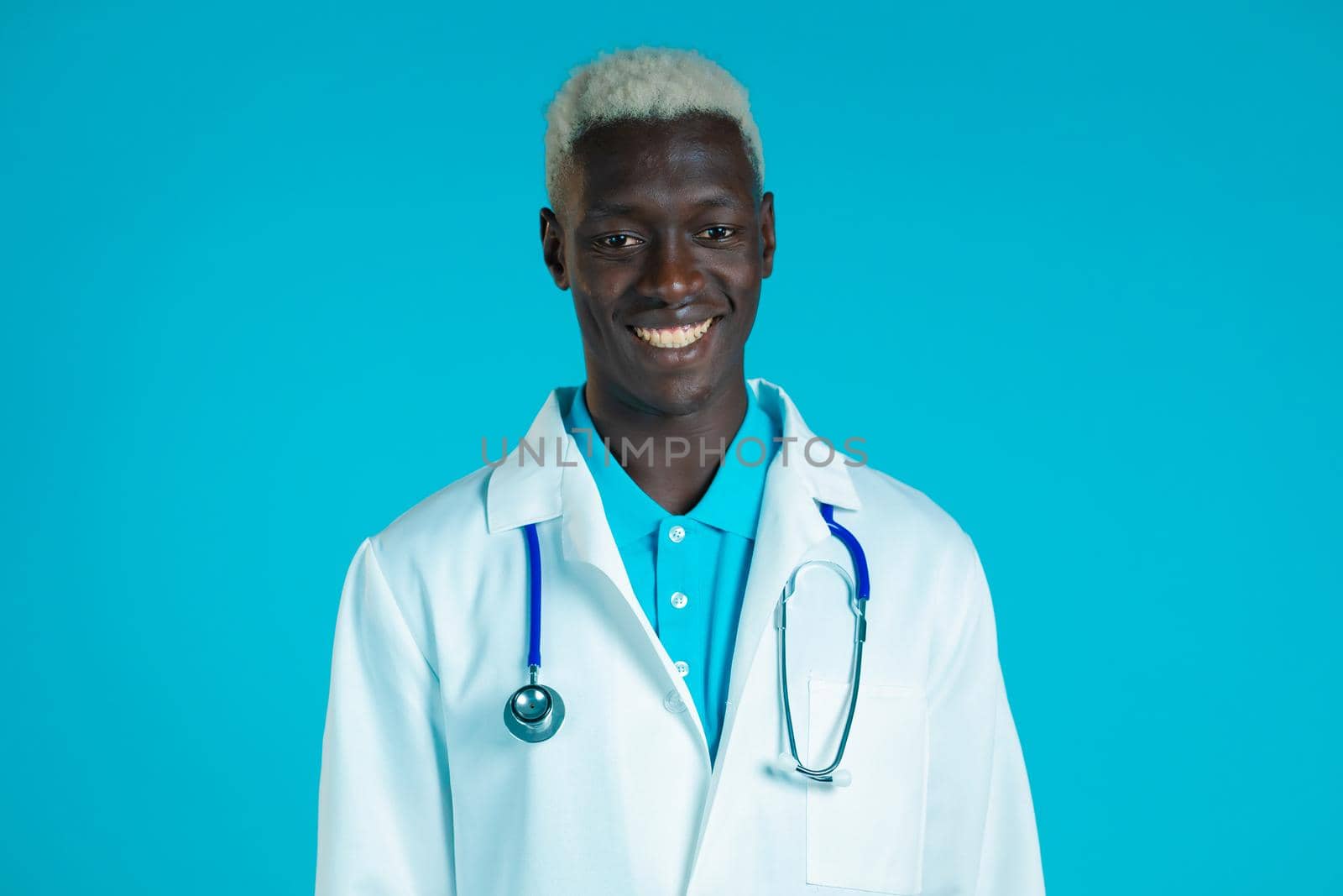 Portrait of smiling african doctor in professional medical coat . Doc man isolated on blue background