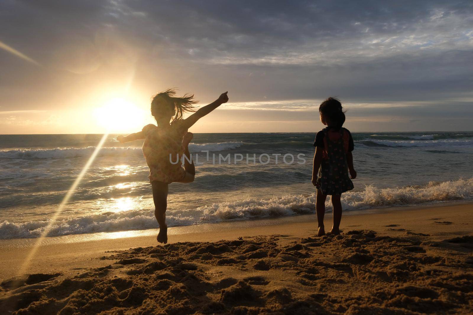 Cute Asian sisters playing on the beach during summer vacation at sunset together. Summer family trip to the beach. travel and vacation concept.