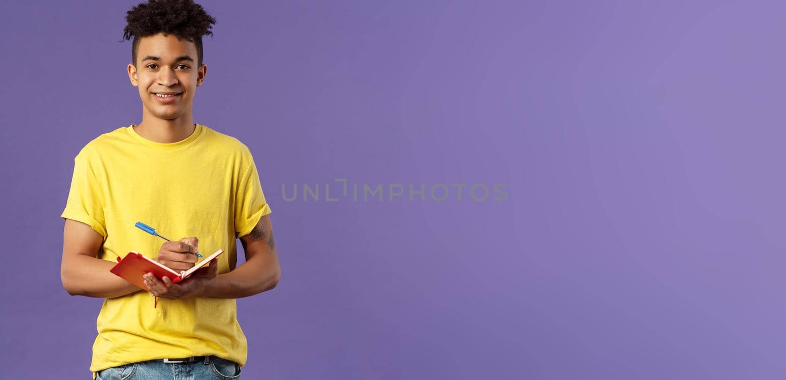 Portrait of young hispanic male student studying online courses, writing down lecture, making personal schedule or taking notes in planner, look camera enthusiastic and interested, purple background. by Benzoix