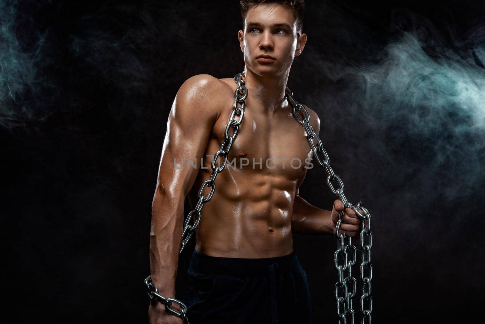Teenager men sportsmen. Portrait of a brutal boy with chains. Athlete bodybuilder on black background. by MikeOrlov