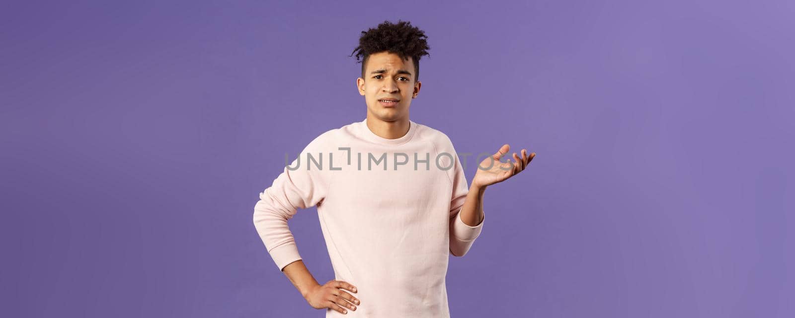 So what, why asking. Portrait of unbothered and careless, ignorant young man dont care on people rules, raising hand in dismay and confusion, being puzzled, look uninterested, purple background.