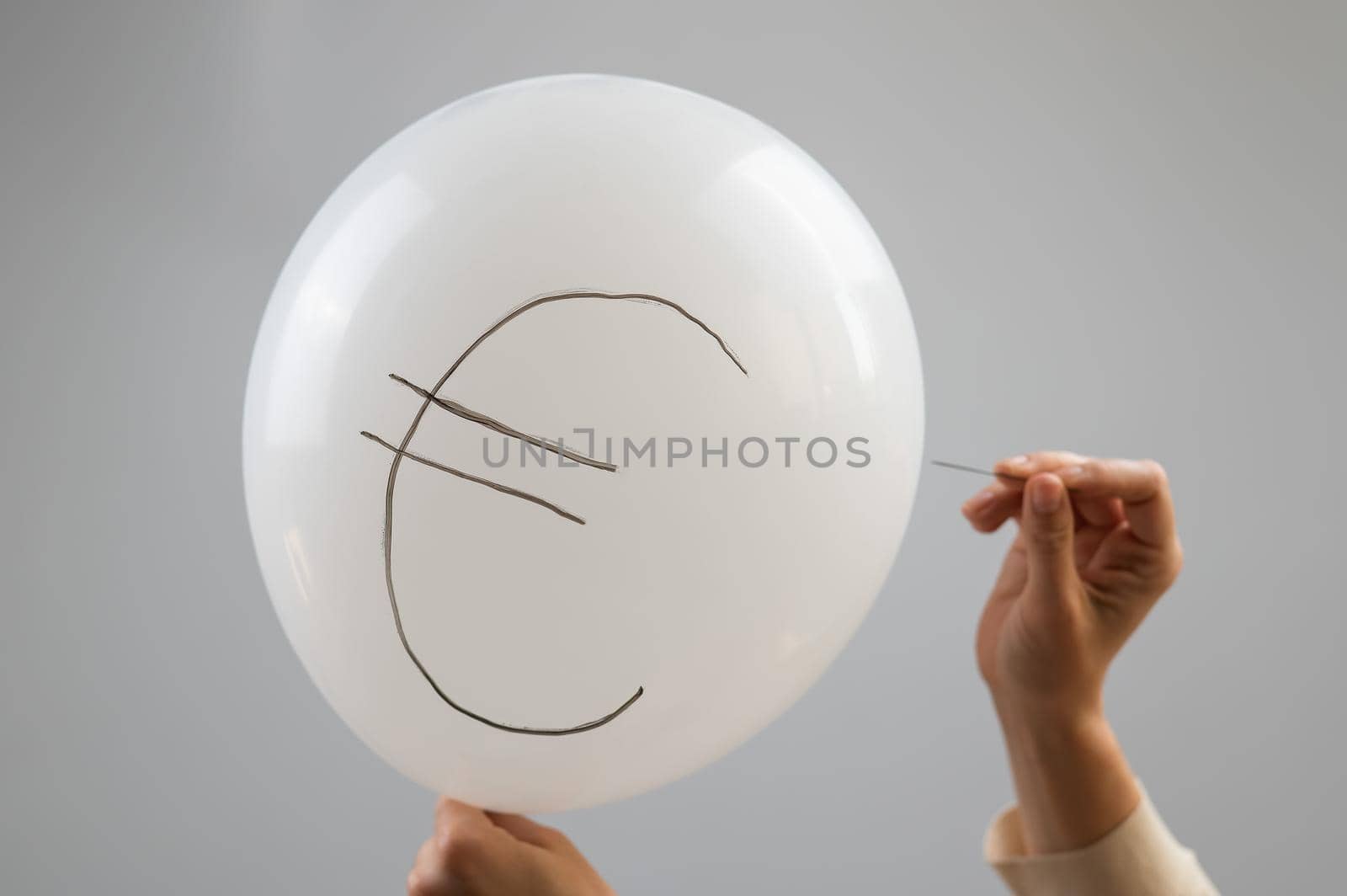 A woman bursts with a needle a balloon with the inscription euro