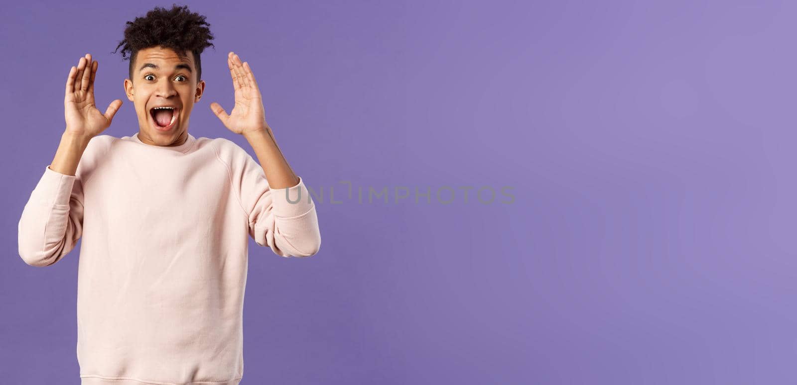 Portrait of happy surprised young man, celebrating birthday, open his eyes to see something really awesome, receive incredible gift, being astounded and speechless from joy and happiness.