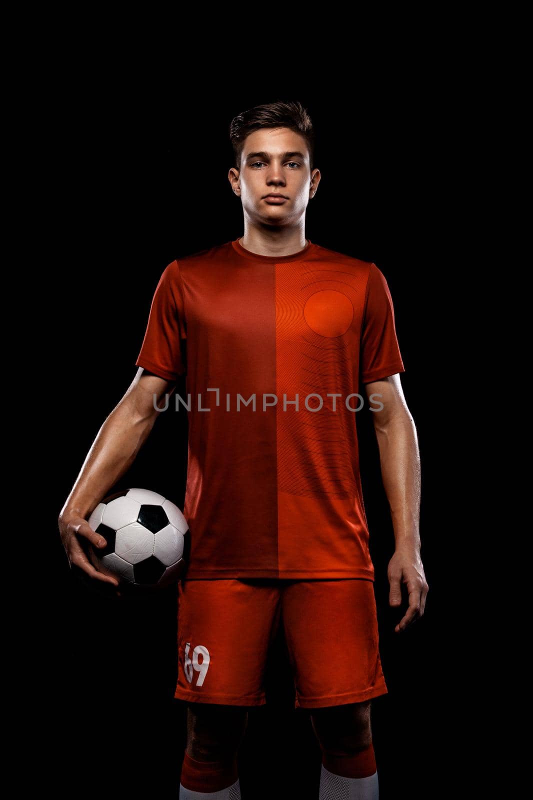 Kids in soccer sportswear on stadium with ball.