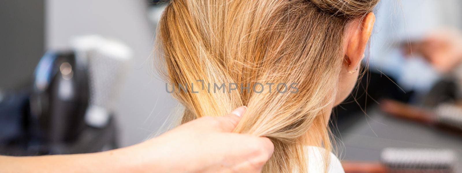 Close up of hands of female hairdresser styling hair of a blonde woman in a hair salon