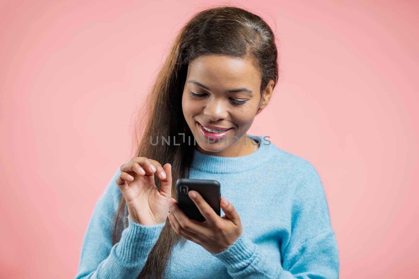 African woman using smartphone on pink studio wall. Using modern technology - apps, social networks. 4k