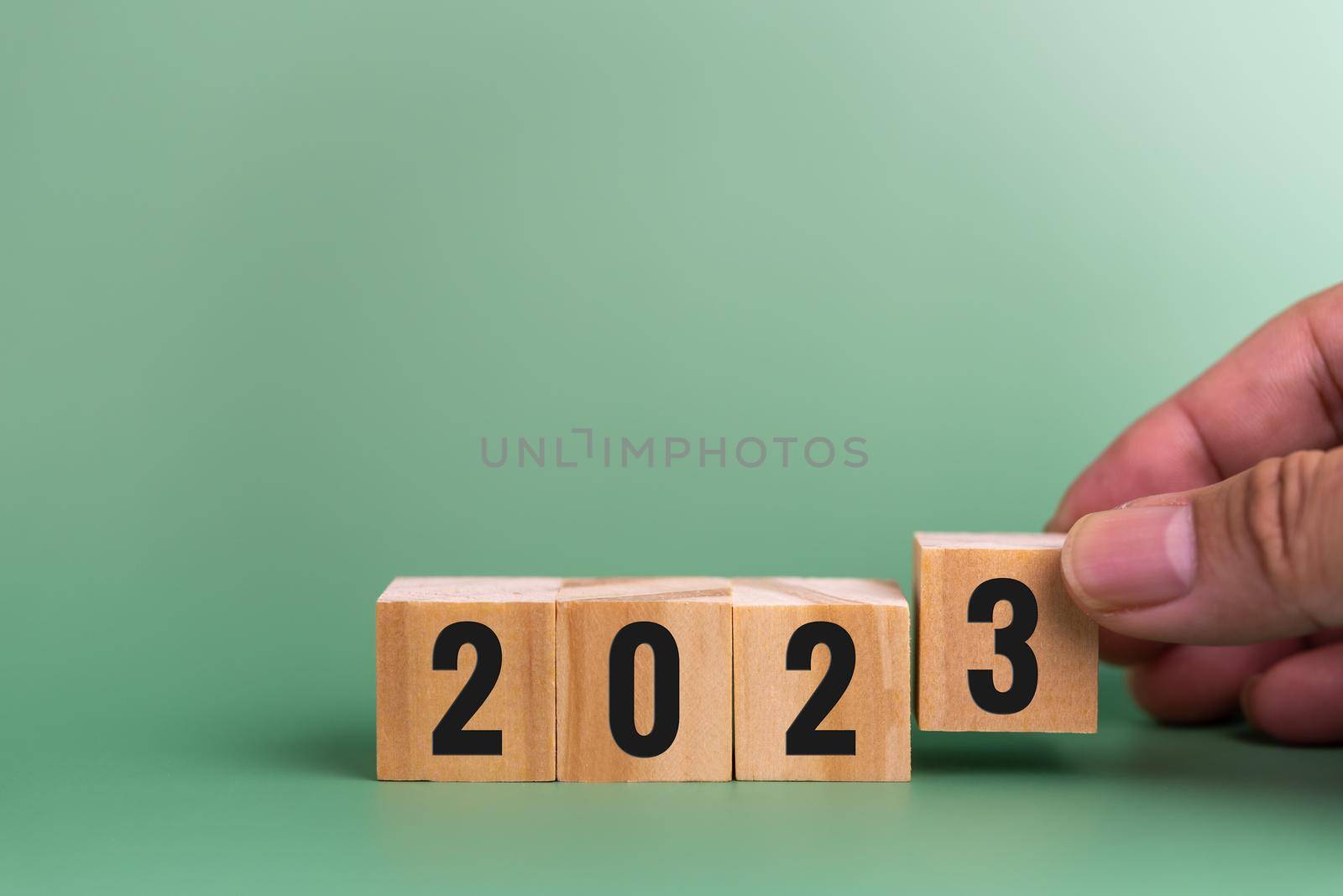 Man hand holding wood cube text 2023 target strategy business concept on green background.