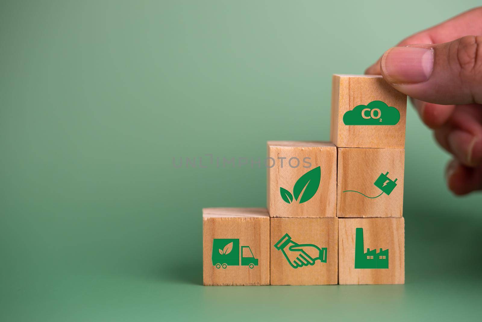 Hand holding wood cube block icon co2 carbon credit and eco energy green technology on green background. by aoo3771