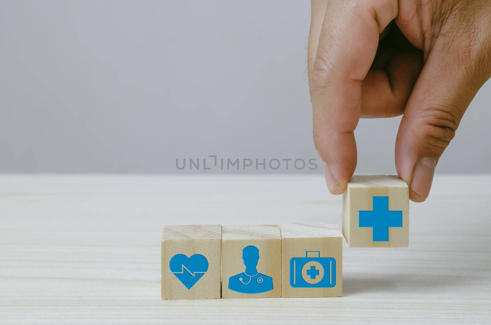 Hand holding wooden cubes block with insurance health car medical symbol on background and copy space. by aoo3771