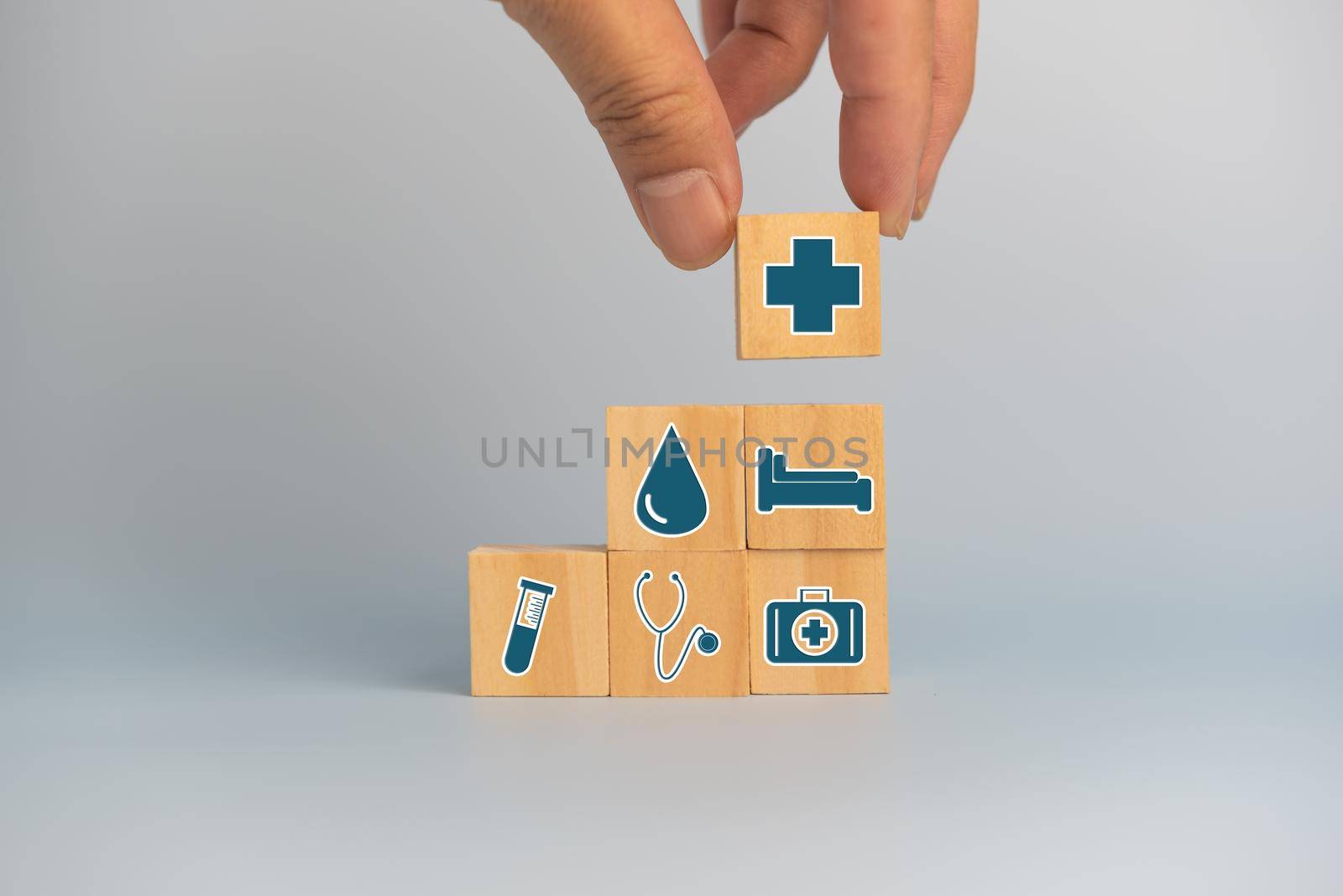 Hand holding wooden cubes block with insurance health car medical symbol on background and copy space.
