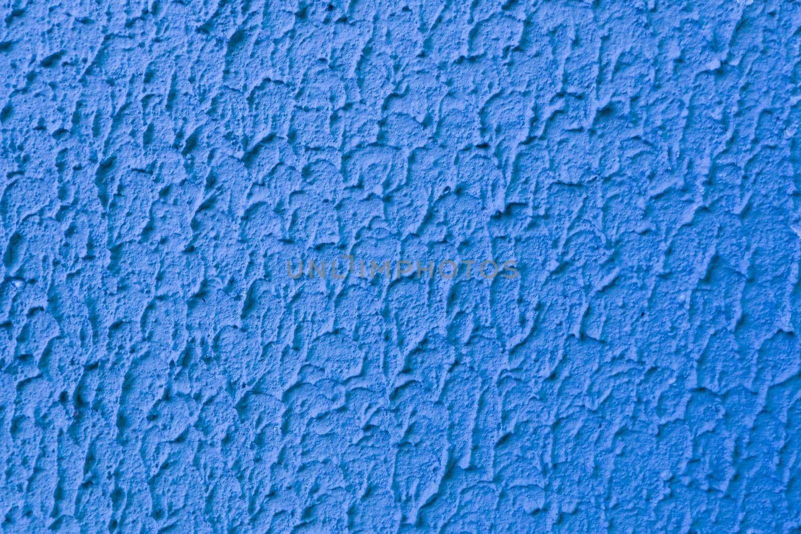 Abstract texture of embossed blue plaster on concrete wall.