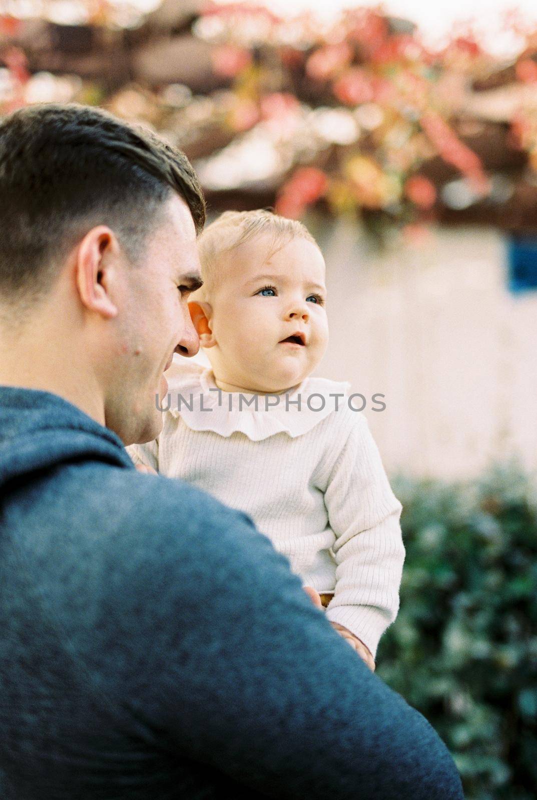 Dad looks at the baby in his arms. Back view by Nadtochiy