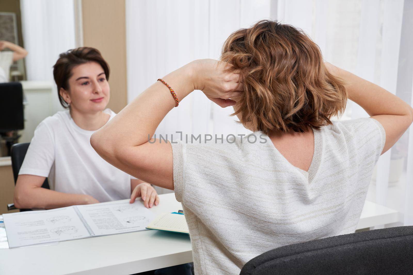 Doctor or massage specialist consulting young woman about her headache