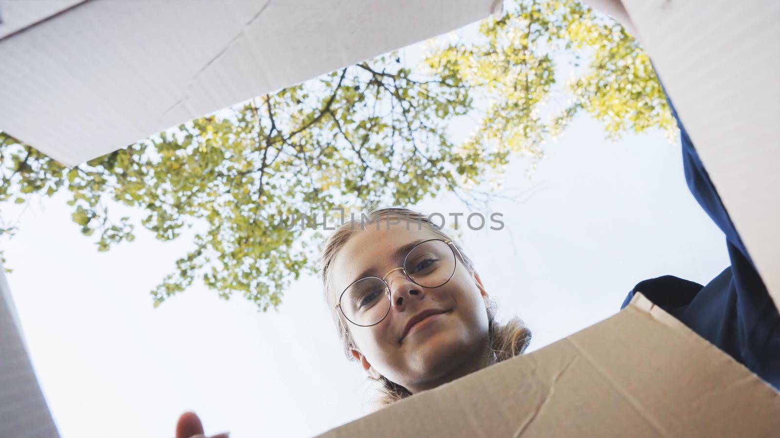 A girl opens a box in the park in admiration