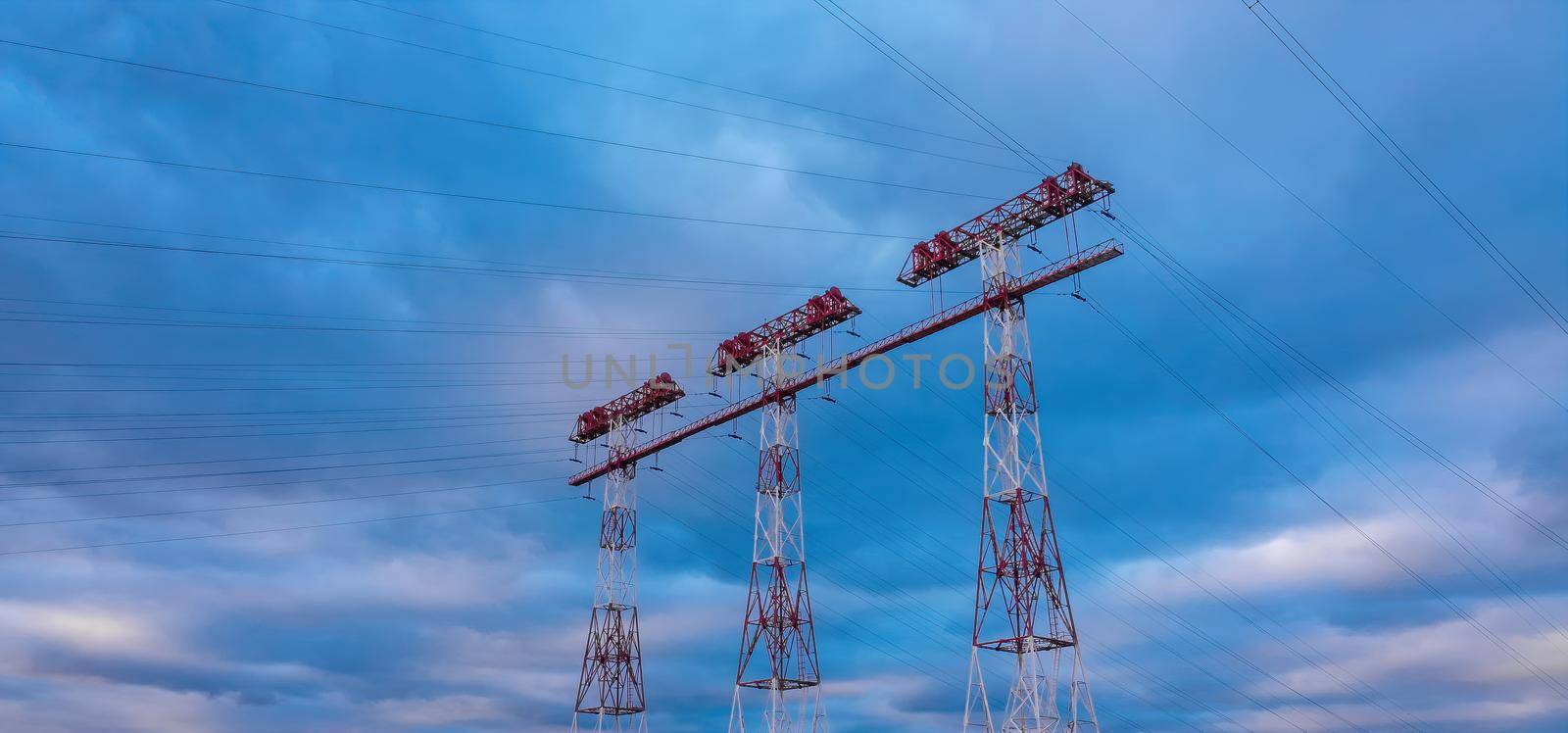 High voltage lines and power pylons in a sunset. landscape with clouds and blue sky. by igor010