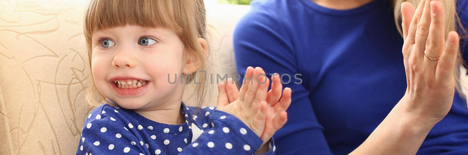 Cute little girl plays with mom and claps hands. Home games with young children concept