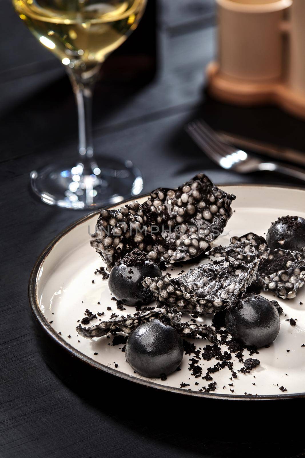 Appetizer with salmon pate, ink cuttlefish, crackers served on white tray over black wooden background. Close-up by nazarovsergey