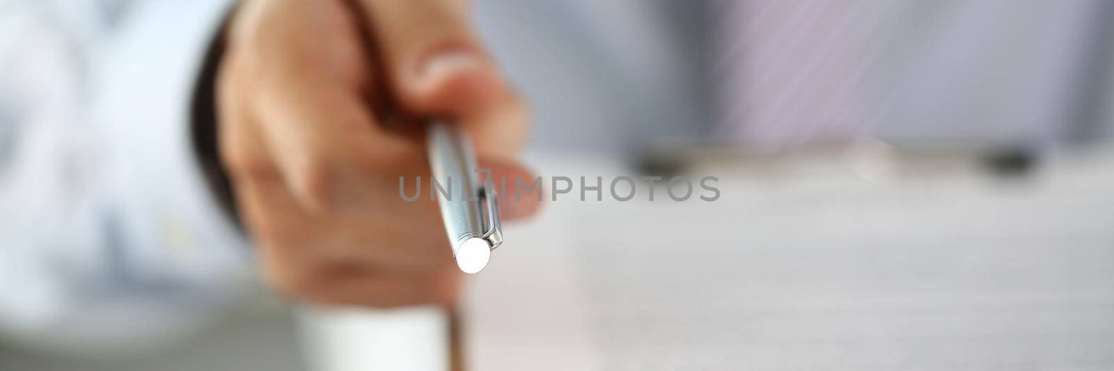 Man hand holds out pen to sign contract. Make deal with profit concept