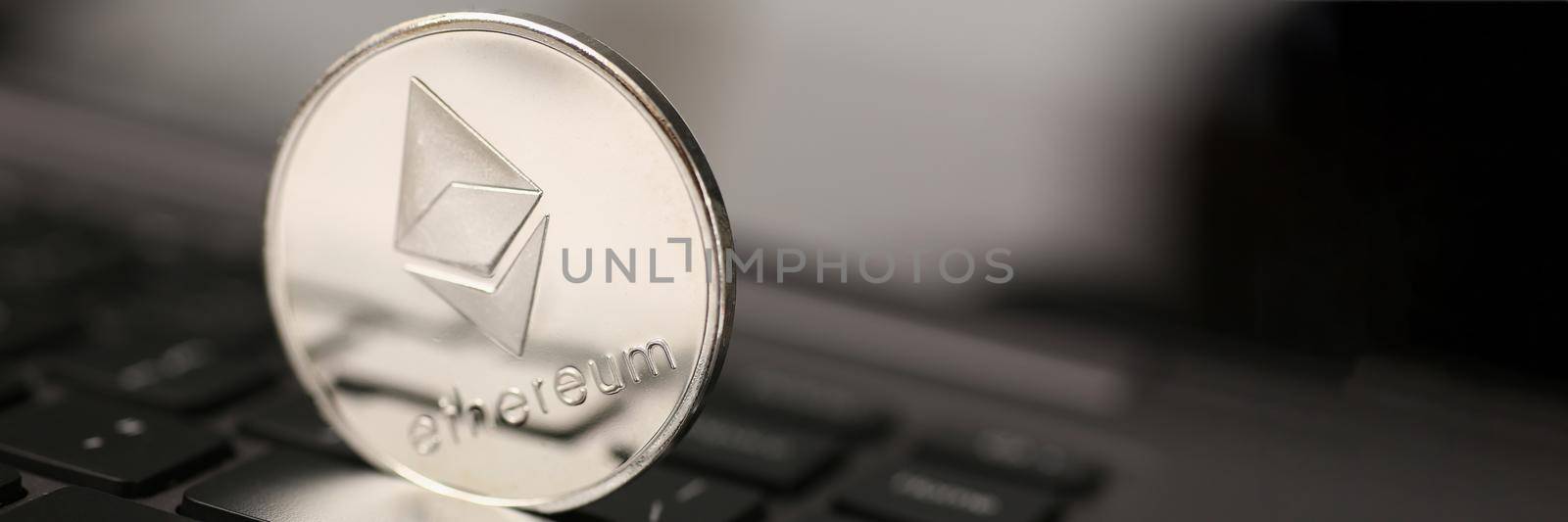 Ethereum silver coin on laptop pc keyboard. Future web ico new type of money eth btc free fast trading concept