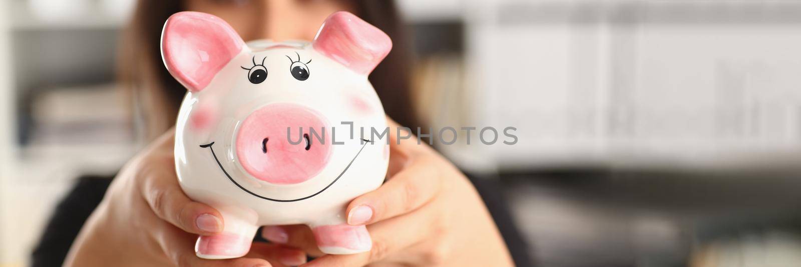 Young woman holding piggy bank in hands pink pig piggy bank. Accumulation of funds concept