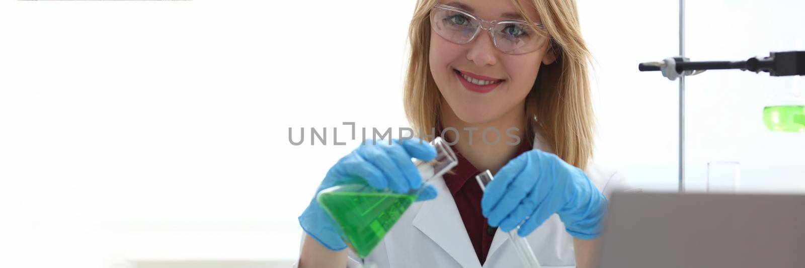 Scientist holds bottle with sample with toxic green liquid in hands in protective gloves. Toxic substances and liquids concept