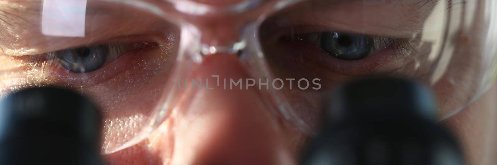 Male scientist looks through binocular microscope and studies disease of virus by kuprevich