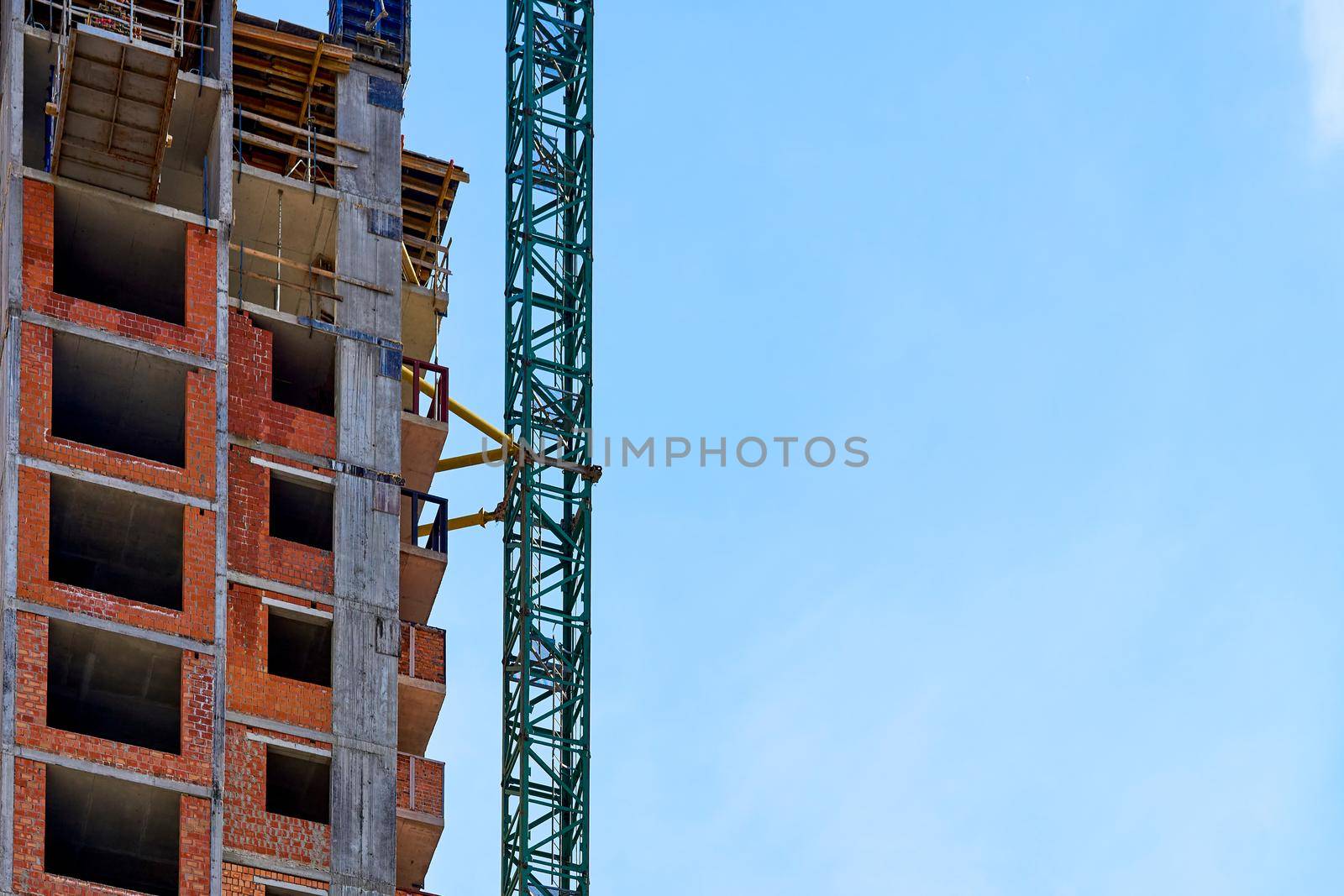 a large, tall machine used for moving heavy objects by suspending them from a projecting arm or beam. Construction high crane,building and blue cloud sky