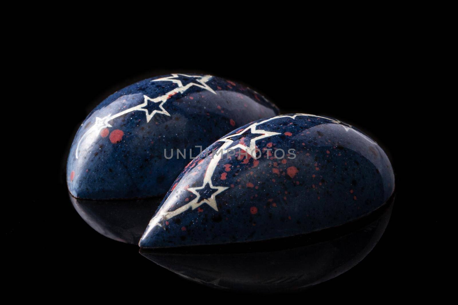 Dark blue luxury handmade chocolate candies with white stars on black background. Exclusive handcrafted bonbon. Product concept for chocolatier