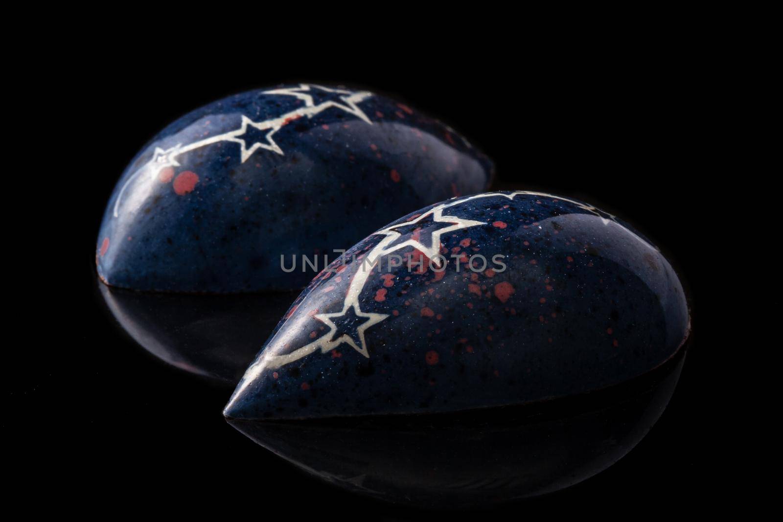 Dark blue luxury handmade chocolate candies with white stars on black background. Exclusive handcrafted bonbon. Product concept for chocolatier