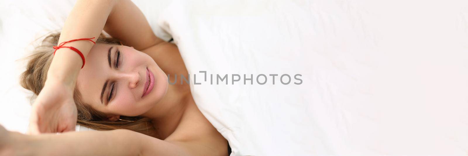 Young smiling happy woman wakes up in morning in bed. Positive mood with morning concept