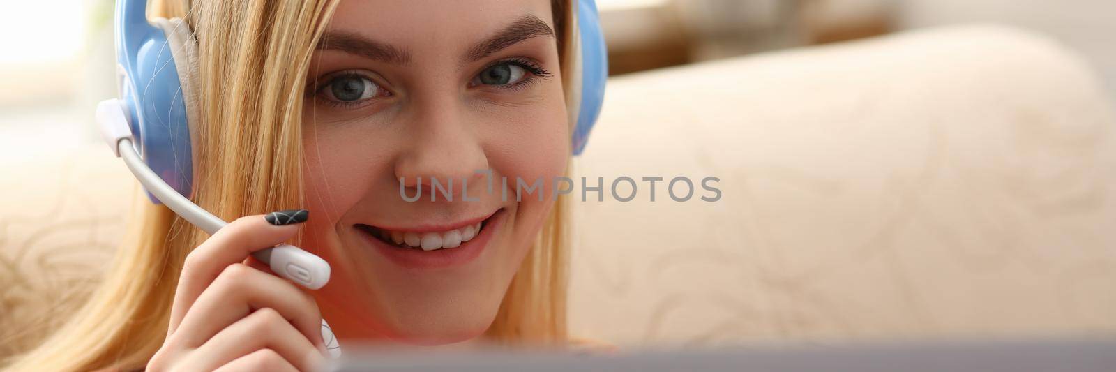 Portrait of happy young caucasian woman in headphones talking online with client via digital webcam. Remote communication concept