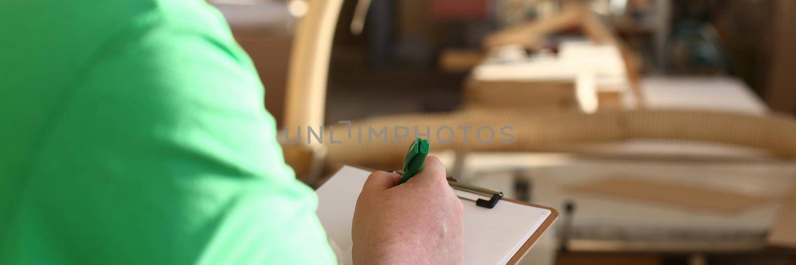 Worker with clipboard draws up order for production of furniture closeup by kuprevich