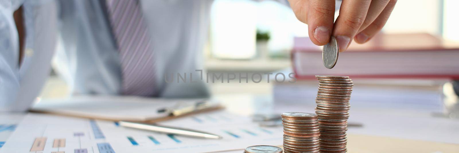 Businessman puts coin into stack of coins. Profit increase and investment investment concept