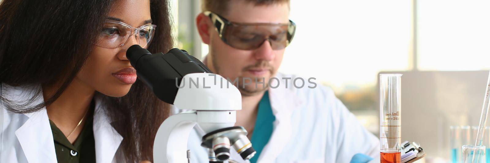 Two chemistry students conduct microscopic examinations in laboratory by kuprevich