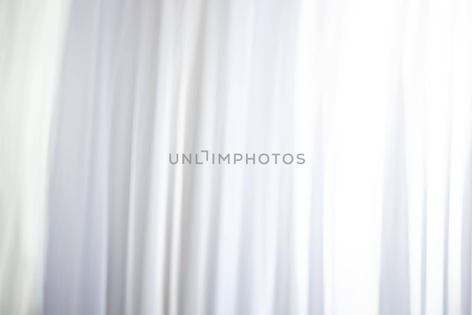 Background of white curtains with a gleam from the window, waves and folds with soft blur. Backdrop
