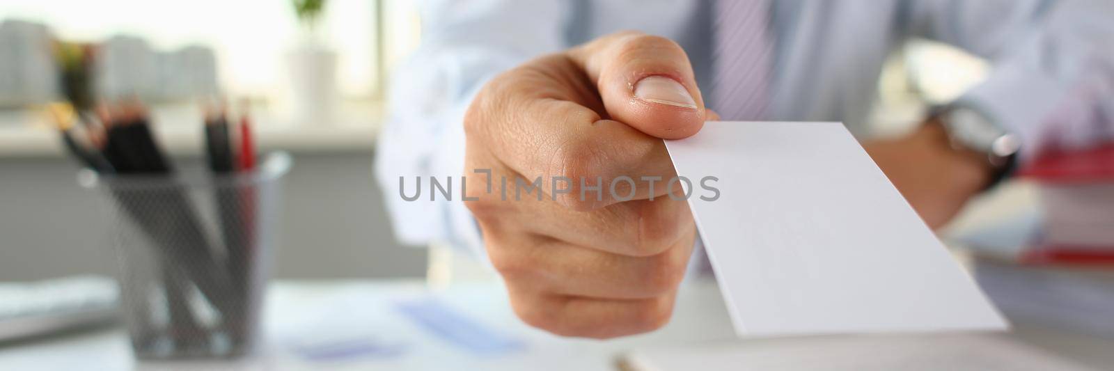 Businessman holds business card in hand closeup by kuprevich