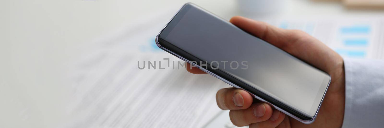 Businessman holds in hand new modern smartphone. Choosing smartphone for work concept