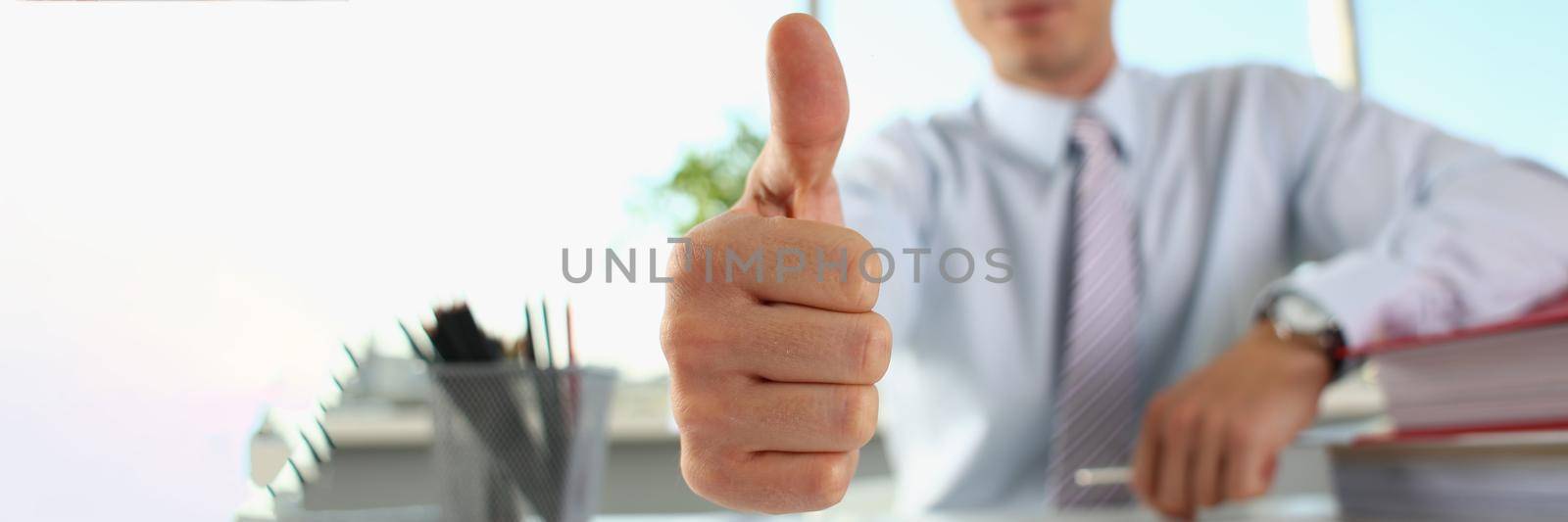 Businessman makes thumbs up gesture closeup. Successful career by kuprevich