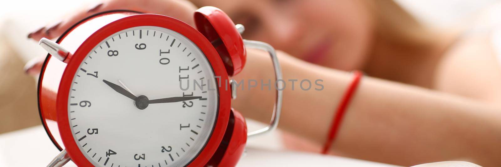 Young woman wakes up from morning alarm clock. Early awakening and fatigue concept