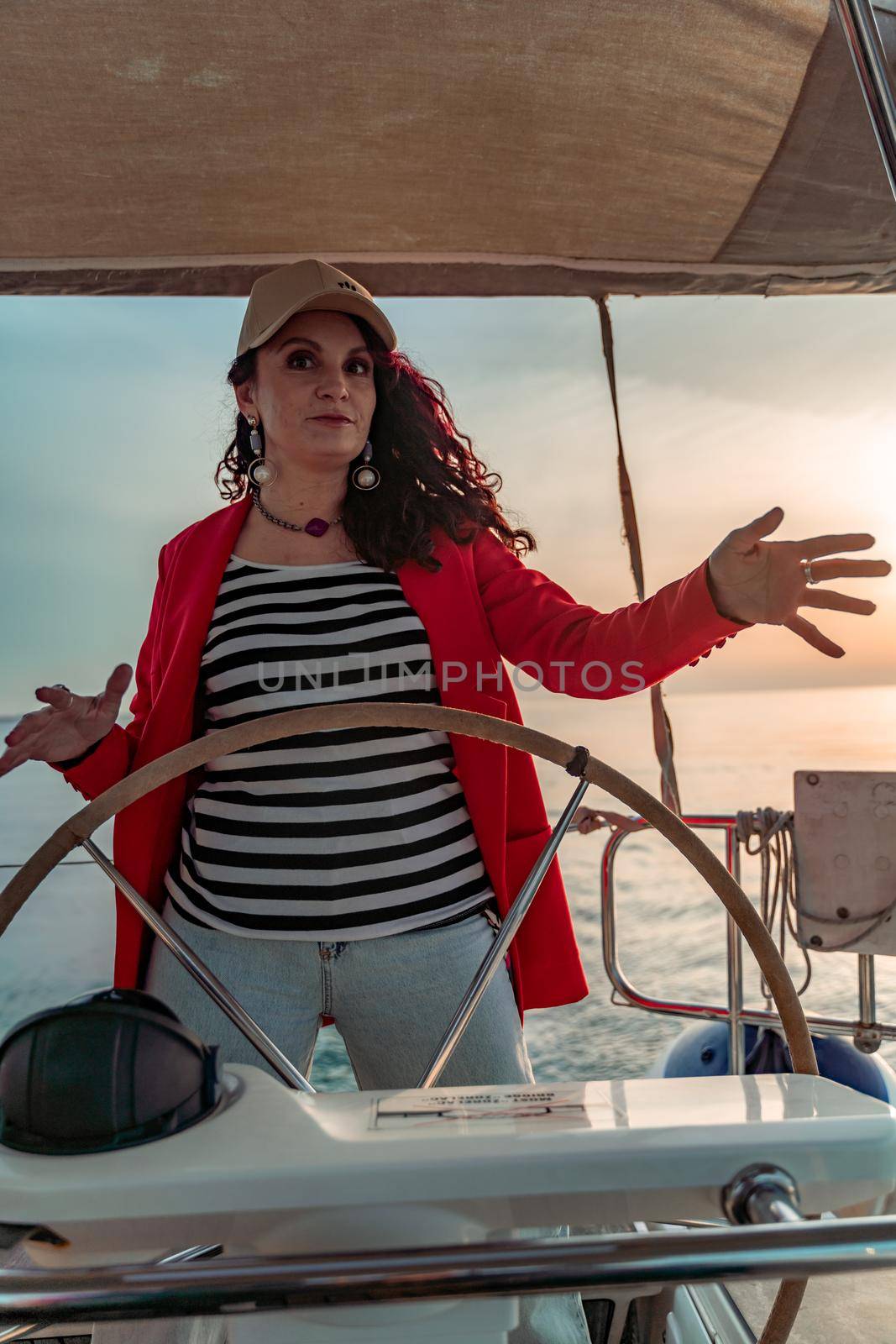 Attractive middle-aged woman at the helm of a yacht on a summer day. Luxury summer adventure, outdoor activities