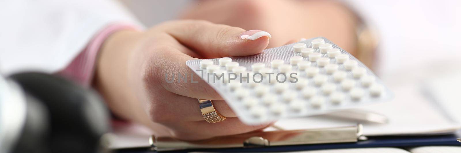 Doctor hand holding package of pills in workplace closeup. Medicines concept