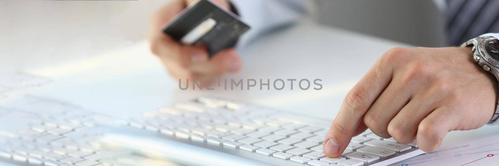 Male hands holding a bank credit card and working on computer keyboard by kuprevich