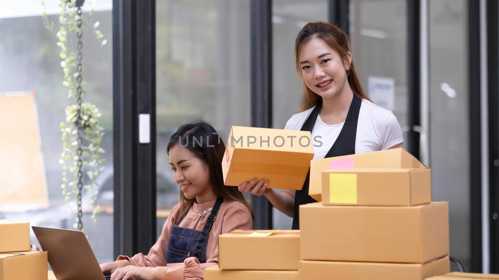 Portrait of Asian young woman SME working with a box at home the workplace.start-up small business owner, small business entrepreneur SME or freelance business online and delivery concept. by wichayada