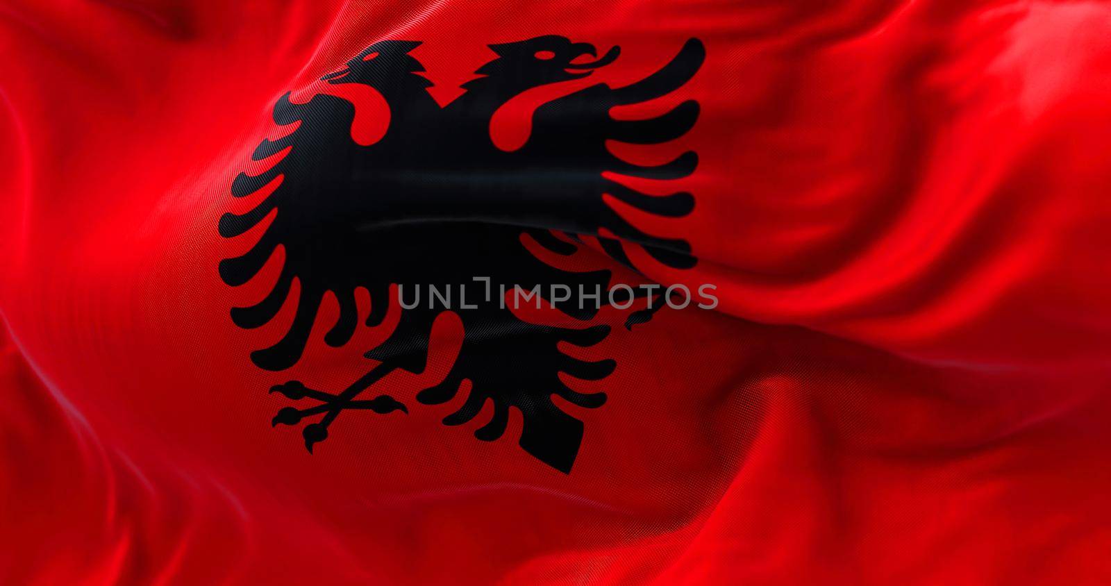 Close-up view of the Albanian national flag waving in the wind. Albania is a country in Southeastern Europe. Fabric textured background. Selective focus