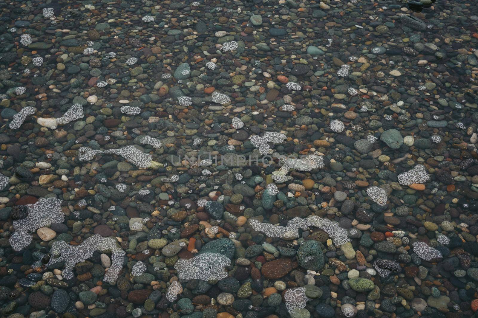 Pebble beach flooded with water after high tide, natural rounded gravel on the seashore nature background