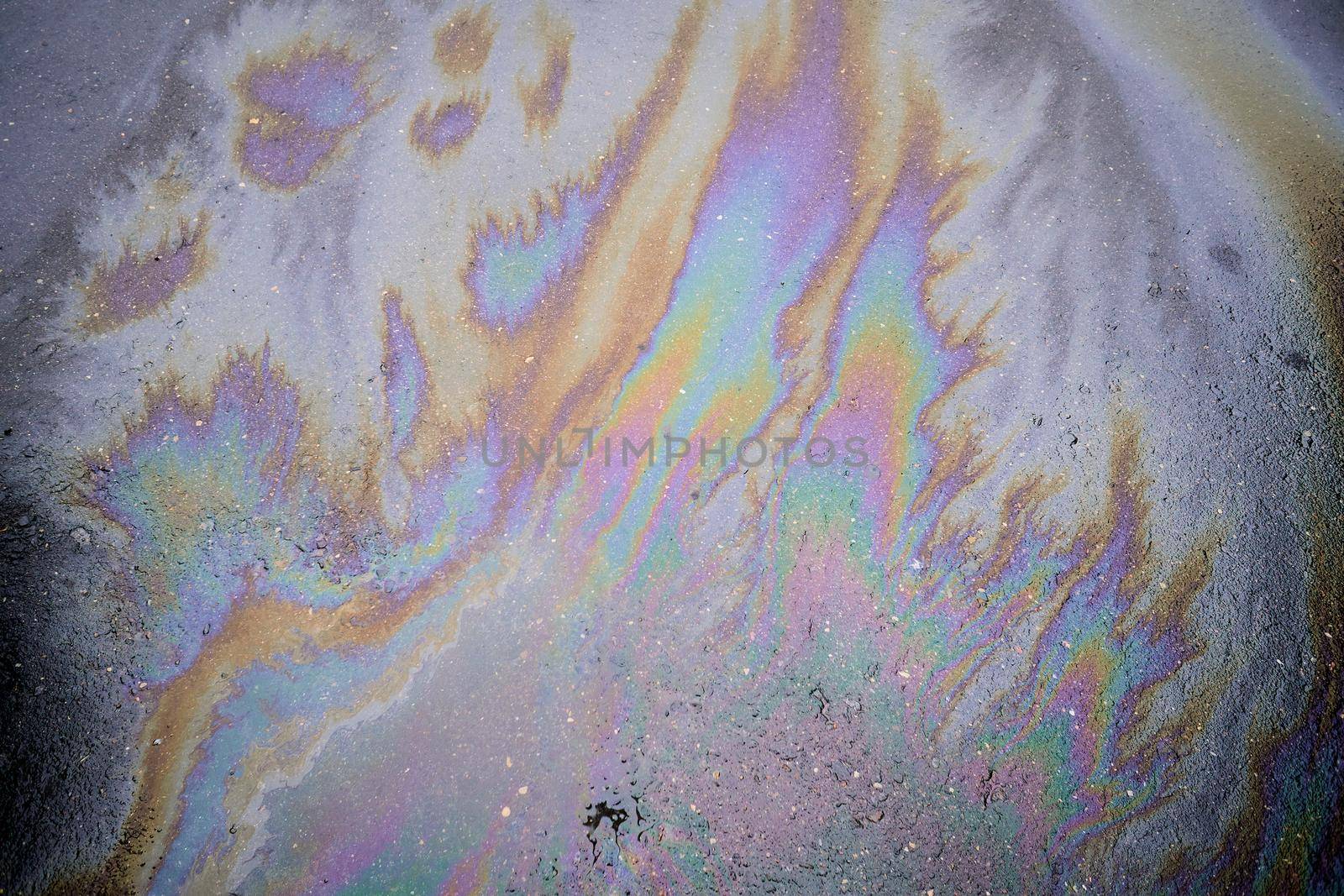 Oil stain on the asphalt, rainbow-shaped colored gasoline stains on an asphalt road as a texture or background