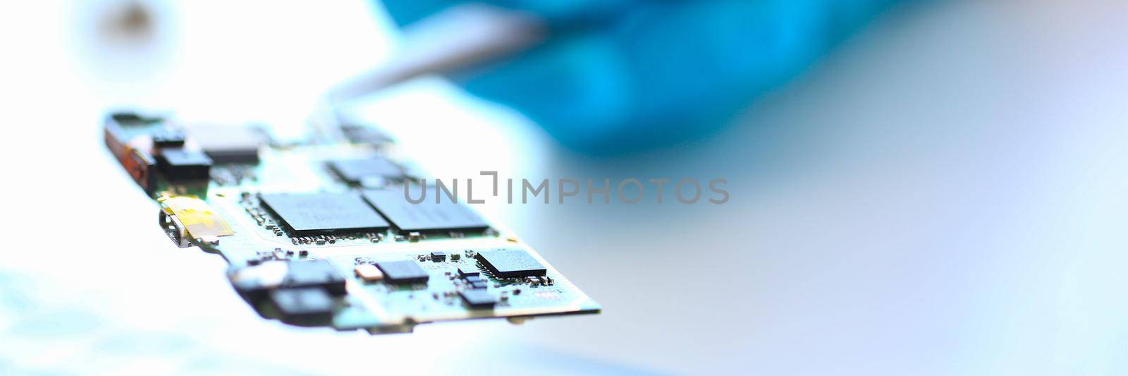 Engineer holds motherboard processor spare part with tweezers by kuprevich