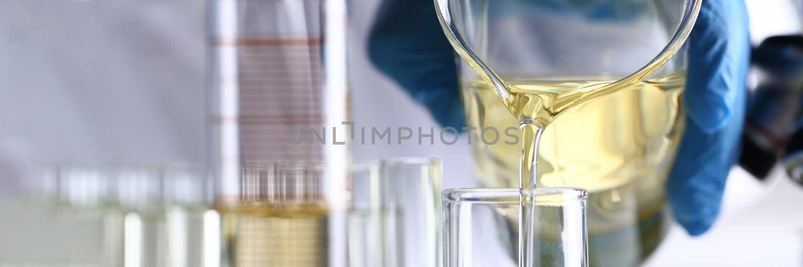 Hand pours yellow liquid into test tube. Conveyor line for the production of household cleaning products concept